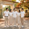 Năm cựu học sinh mặc áo polo trắng phối cổ be sọc đen quàng vai nhau trước cổng trường trong ngày họp lớp 10 năm